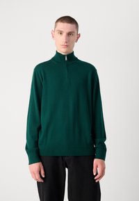 Sweater verde con zip, realizzato in tessuto morbido, dotato di colletto alto, maniche lunghe e polsini a coste. Design minimalista senza pattern visibili.