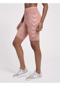 Pink patterned compression shorts with a high waistband, featuring a herringbone design and smooth texture, paired with gray athletic shoes.