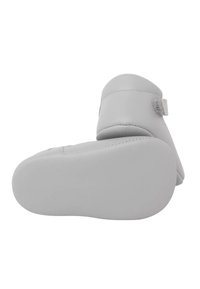 Scarpina per bambino in pelle grigia con suola morbida, punta rotonda e cinturino in Velcro; texture liscia e design semplice senza motivi o decorazioni.