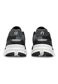 Zwarte sportieve schoenen met een gestructureerde mesh bovenkant, grijze accenten, witte tussenzool en zwarte rubberen buitenzool. Bevat logo-details op de hiel.
