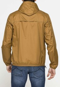 Giacca leggera marrone con cappuccio, polsini ed elastico in vita. Texture liscia e lucida. Dettaglio di cucitura sulla parte superiore della schiena.