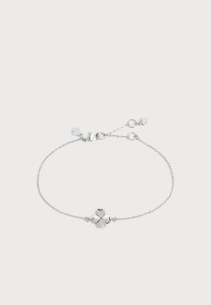 Bracelet chaîne en argent délicat avec un pendentif trèfle à quatre feuilles au centre et un petit cristal rond près du fermoir.