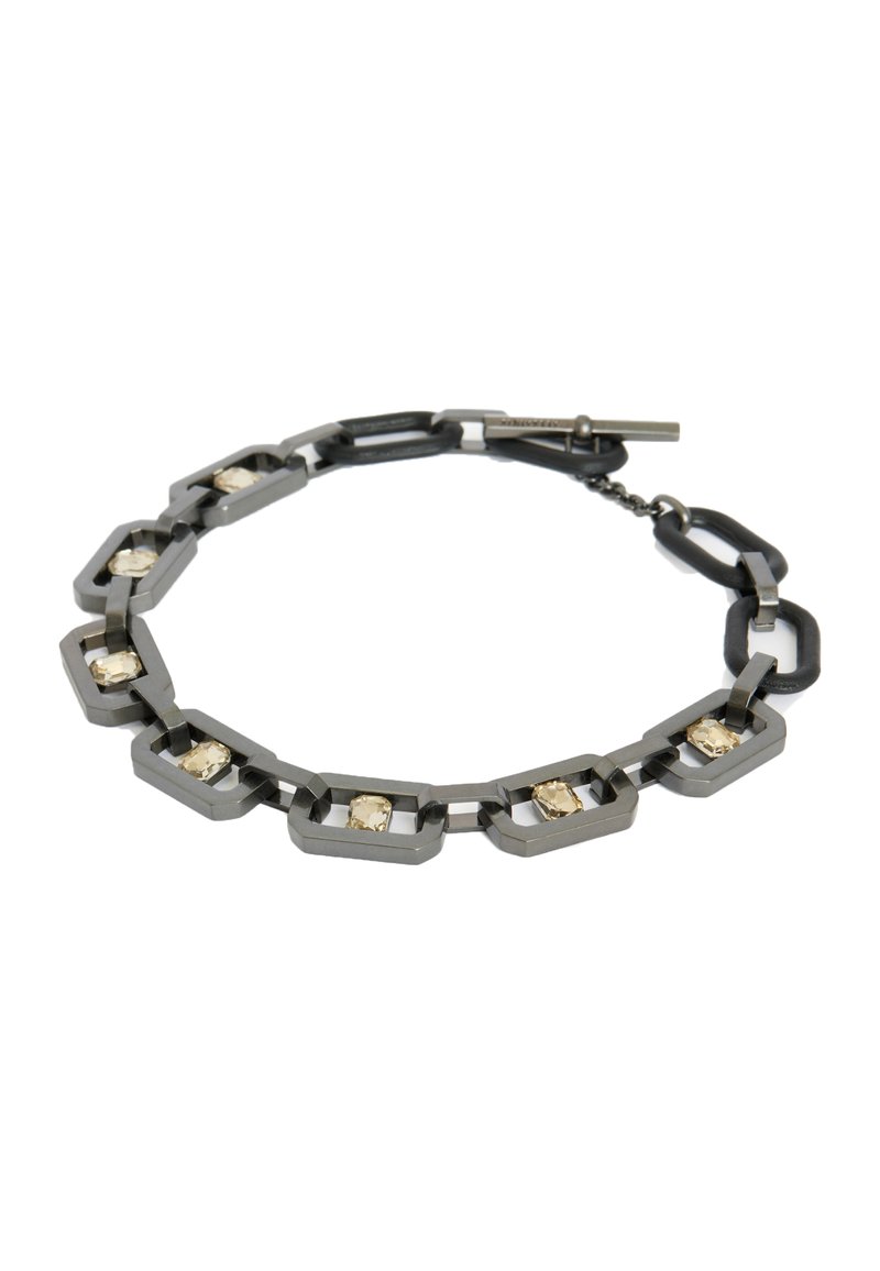 Metal bracelet featuring interlocking hexagonal links in dark gray, embellished with light-colored rectangular stones. Secure toggle closure.