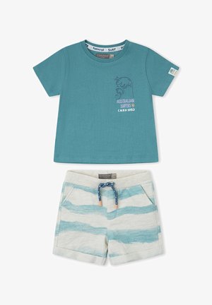 Camiseta de manga corta en color teal con gráfico de ola y texto, combinada con pantalones cortos blancos con rayas teal y cordón azul.