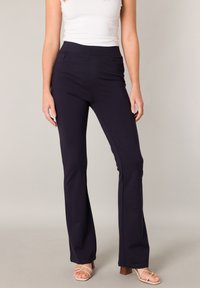 Marineblaue Schlaghose mit breitem elastischem Bund, ausgestattet mit zwei Seitentaschen und glattem, dehnbarem Stoff. Keine sichtbaren Muster oder Logos.