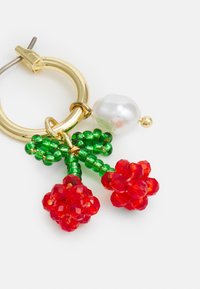 Os brincos de argola dourada apresentam flores de cristal vermelho, folhas de contas verdes e um detalhe de pérola branca. Cores texturizadas e vibrantes com um design botânico.