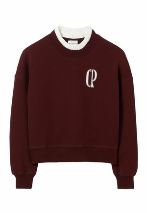 Sweat-shirt bordeaux à design court, avec un col et des poignets côtelés. Il présente un logo brodé "CP" sur le devant. Matériau en coton.