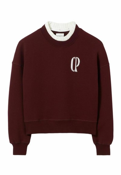 Sudadera burdeos con un diseño recortado, cuello y puños acanalados. Presenta un logo bordado "CP" en el frente. Material de algodón.
