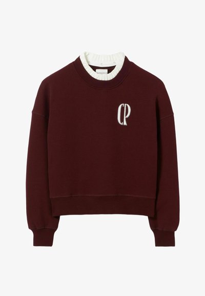 Felpa bordeaux con un design corto, colletto e polsini a costine. Presenta un logo ricamato "CP" sulla parte anteriore. Materiale in cotone.