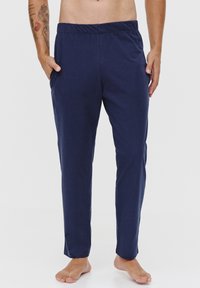 Granatowe, lekkie spodnie dresowe z elastycznym pasem i bocznymi kieszeniami, o luźnym kroju i zwężanych nogawkach.