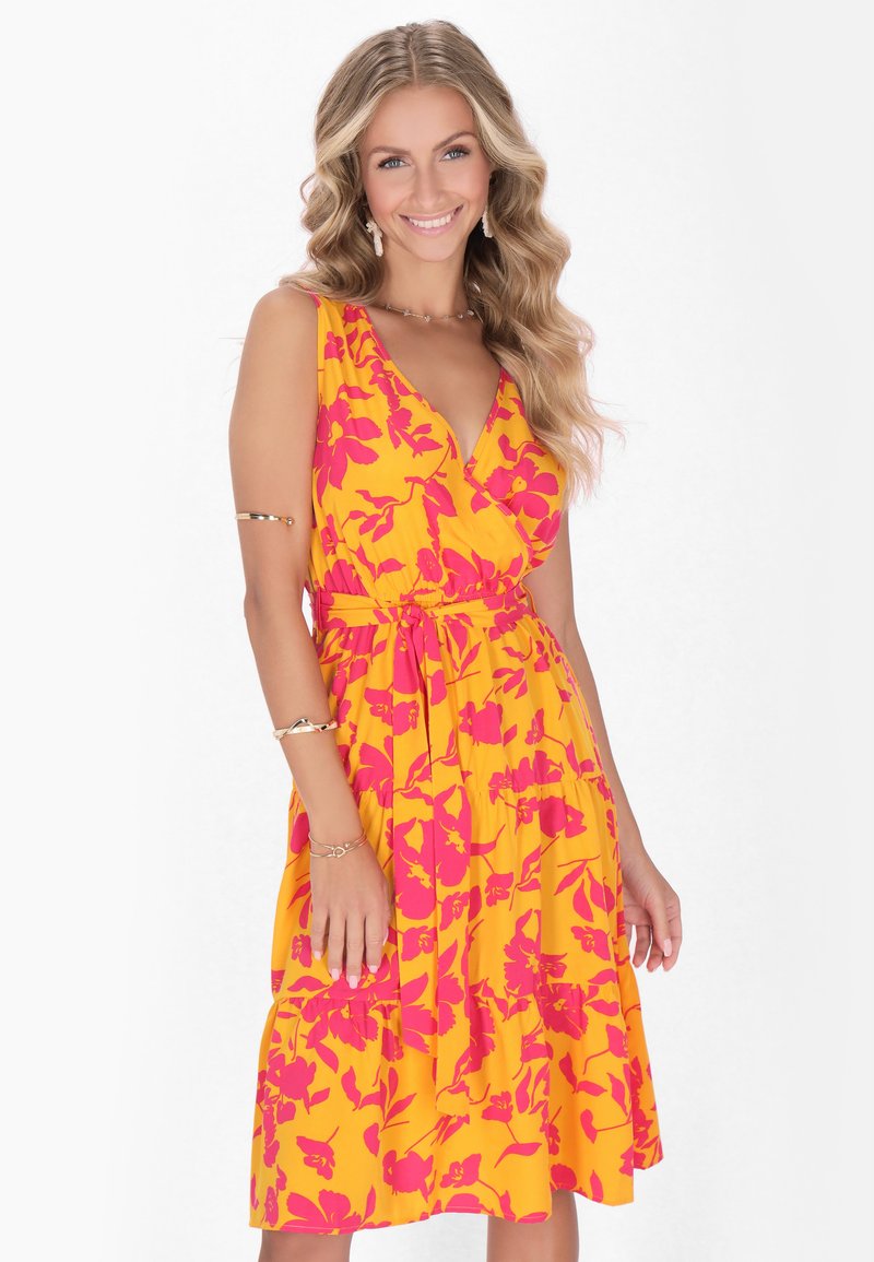 Rochie galbenă cu model floral roz, design fără mâneci, decolteu în V, curea la talie și fustă vaporoasă. Textură netedă, material ușor.