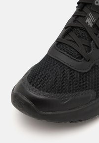 Baskets noires de sport avec une tige en mesh respirant, des accents en cuir lisse et une semelle en caoutchouc texturé avec des détails de marque.