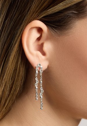 Zilveren oorbellen met cascade kettingen versierd met heldere kristallen, die licht weerkaatsen, bevestigd aan een stud sluiting.