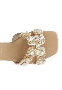 Nude slide sandal med en tjock rem prydd med iriserande stenar och guldfärgade detaljer. Fyrkantig tådesign med slät yta.