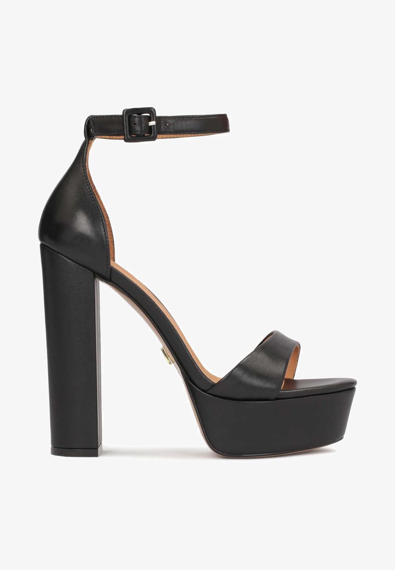 Sandalias de tacón alto de cuero negro con correa al tobillo ajustable, suela con plataforma y tacón grueso. Textura suave con detalles de diseño mínimos.