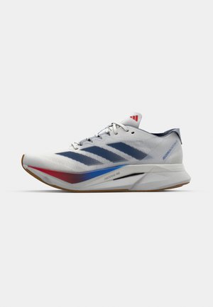 Running shoes with a white mesh upper, blue striped design, red accents, and a light grey sole. Features cushioning for enhanced performance.