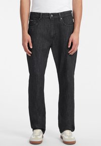 Černé džíny z denimu s rovným střihem, mají přední zapínání na knoflík, pět kapes a nenápadné švy. Nosené se sneakers.