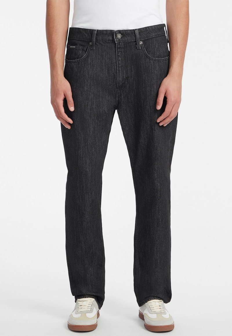 Černé džíny z denimu s rovným střihem, mají přední zapínání na knoflík, pět kapes a nenápadné švy. Nosené se sneakers.