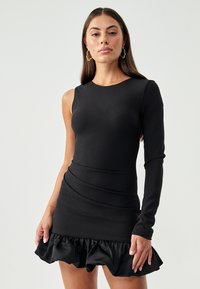 Black dress with a fitted top and one long sleeve, featuring a ruffled hem. Made from a smooth material with a sleek, modern design.