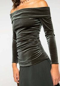 Haut en velours à épaules dénudées de couleur vert foncé avec des manches longues, présentant des détails froncés sur les côtés pour ajouter de la texture et de la forme.