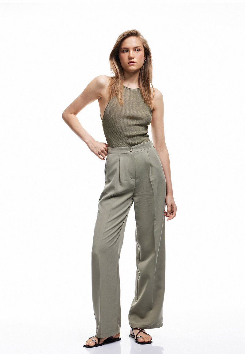 Khaki vidde bukser med frontfolder og en matchende ribbet tanktop. Glat stof og minimal detaljering forbedrer det samlede look.
