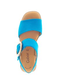 Blauwe suede sandaal met een brede teenband, verstelbare enkelband, grote gespdetails en een bruine binnenzool. Merkennaam "Gabor" zichtbaar op de binnenzool.