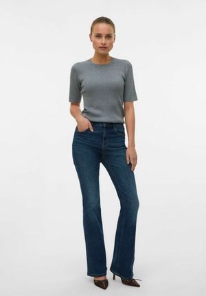 Top gris de punto acanalado de manga corta combinado con jeans acampanados de color azul oscuro, que cuentan con bolsillos frontales y un ligero lavado para darle textura.