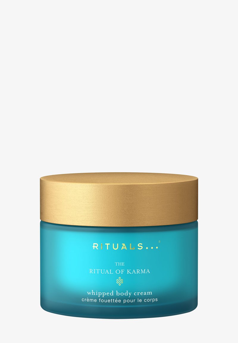 En turkos glasburk med ett guldock, märkt "RITUALS THE RITUAL OF KARMA Whipped Body Cream", med klar text och minimalistisk design.