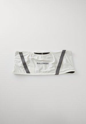 Ceinture en tissu blanc avec des rayures verticales réfléchissantes grises et le logo "Salomon" centré, conçue pour une utilisation en extérieur ou pour le sport.