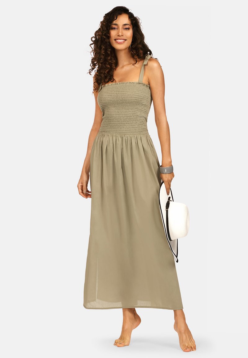 Khaki długa sukienka z marszczonym topem, cienkimi ramiączkami i zwiewnym dołem. Posiada lekką, teksturowaną tkaninę. Stylizowana z białym kapeluszem.