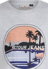 Grijze katoenen T-shirt met een ronde graphic waarop "RETROUR JEANS," palmbomen en een zonsondergang boven een zwembad te zien is.