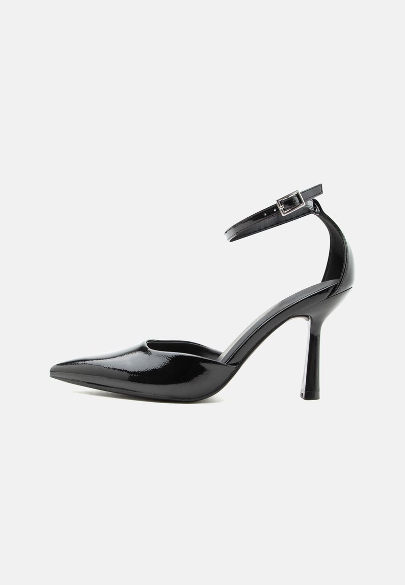Μαύρο παπούτσι με ψηλό τακούνι, μυτερή μύτη από λουστρίνι, με λουράκι στον αστράγαλο και ασημένια αγκράφα, τακούνι στιλέτο, πλευρική όψη σε μονόχρωμο φόντο.