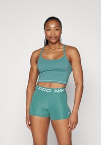 Teal idretts crop topp og shorts-sett, med en tettsittende passform, jevn tekstur og hvit "NIKE PRO" logo på midjebåndet.
