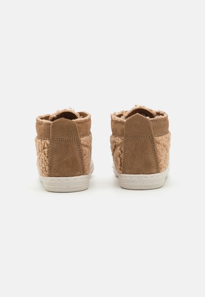 Brown suede ankle boots with a fluffy texture on the sides, a padded collar, and a white rubber sole. Back view showcases stitching detail.