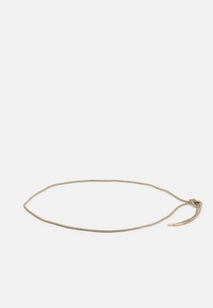 Dunne gouden ketting met een eenvoudige lusknoop en cilindrische metalen uiteinden op een witte achtergrond.