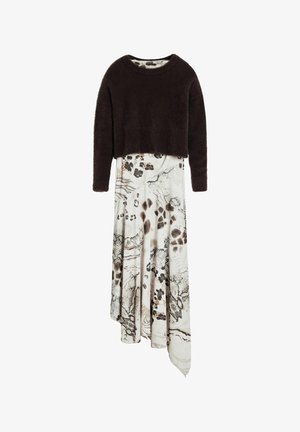 Maglione corto e peloso marrone indossato su un vestito asimmetrico bianco e beige a fantasia, caratterizzato da stampe animalier e drappeggio fluido.