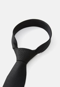 Cravat neagră cu un model texturat, având un finisaj satinat neted și o bandă mai lată în partea de sus, care se subțiază spre un vârf ascuțit.