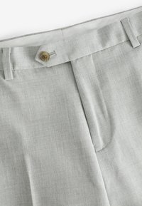 Pantalones gris claro hechos de una tela texturizada, con cierre frontal de botón, bolsillos laterales y un ajuste entallado.