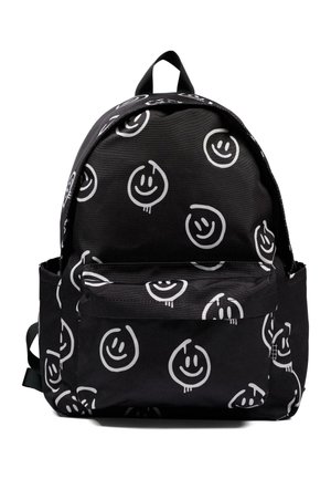 Sac à dos noir avec des visages souriants blancs façon doodle, poche avant, poches latérales et poignée supérieure. Aucun personnage ni élément de fond.