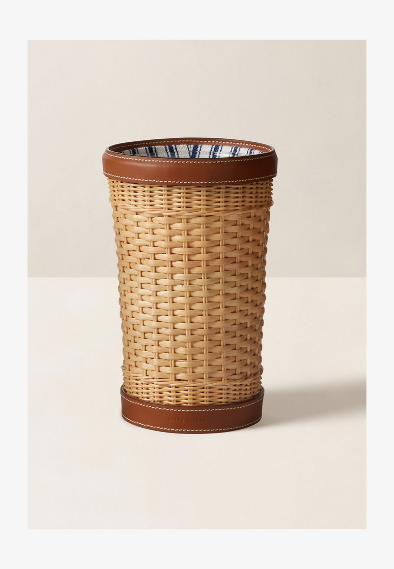 Cesto de lixo em rattan trançado com um acabamento em couro castanho, apresentando uma textura suave e um revestimento interior azul e branco com padrão.