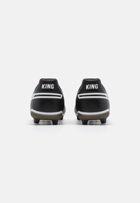 Botas de fútbol negras con una textura suave, con acentos blancos y la palabra "KING" en el talón. Suela con tacos para tracción.