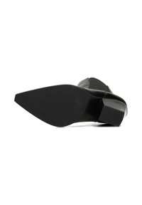 Zapato de tacón alto negro con puntera afilada y tacón cuadrado. Presenta un material de cuero suave y un diseño elegante y minimalista.