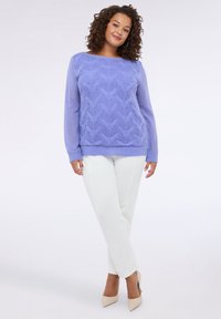 Pulover tricotat de culoare mov deschis, cu o textură în formă de valuri, guler rotund și mâneci lungi, purtat cu pantaloni albi și pantofi cu toc bej.