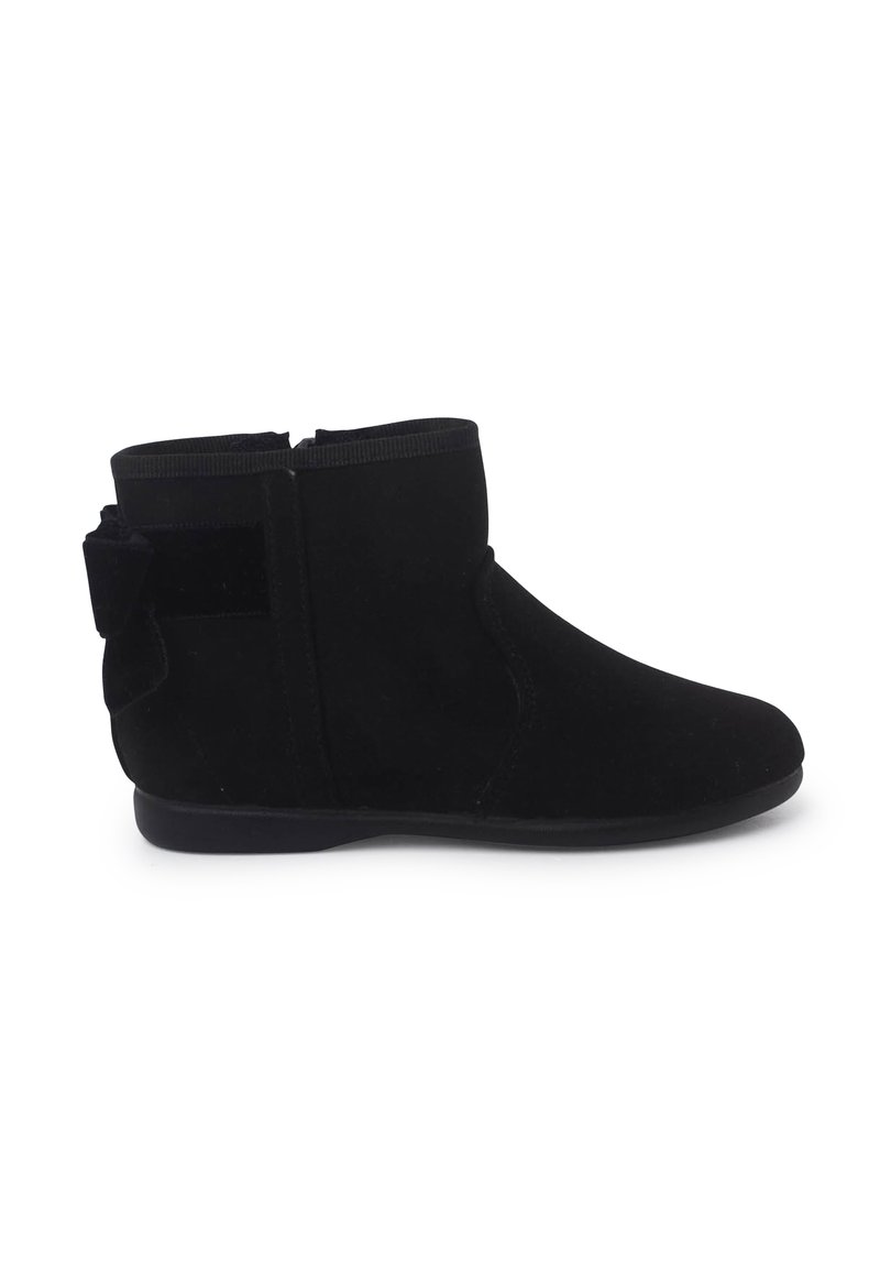 Bottines noires en daim souple avec un bout arrondi, un panneau latéral élastique et un nœud décoratif à l'arrière. Semelle plate en caoutchouc.