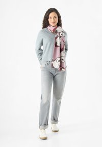 Maglione lavorato a maglia azzurro chiaro con scollo a V, jeans grigi dal taglio rilassato e una sciarpa rosa a fantasia con motivi di animali. Sneakers bianche completano l'outfit.