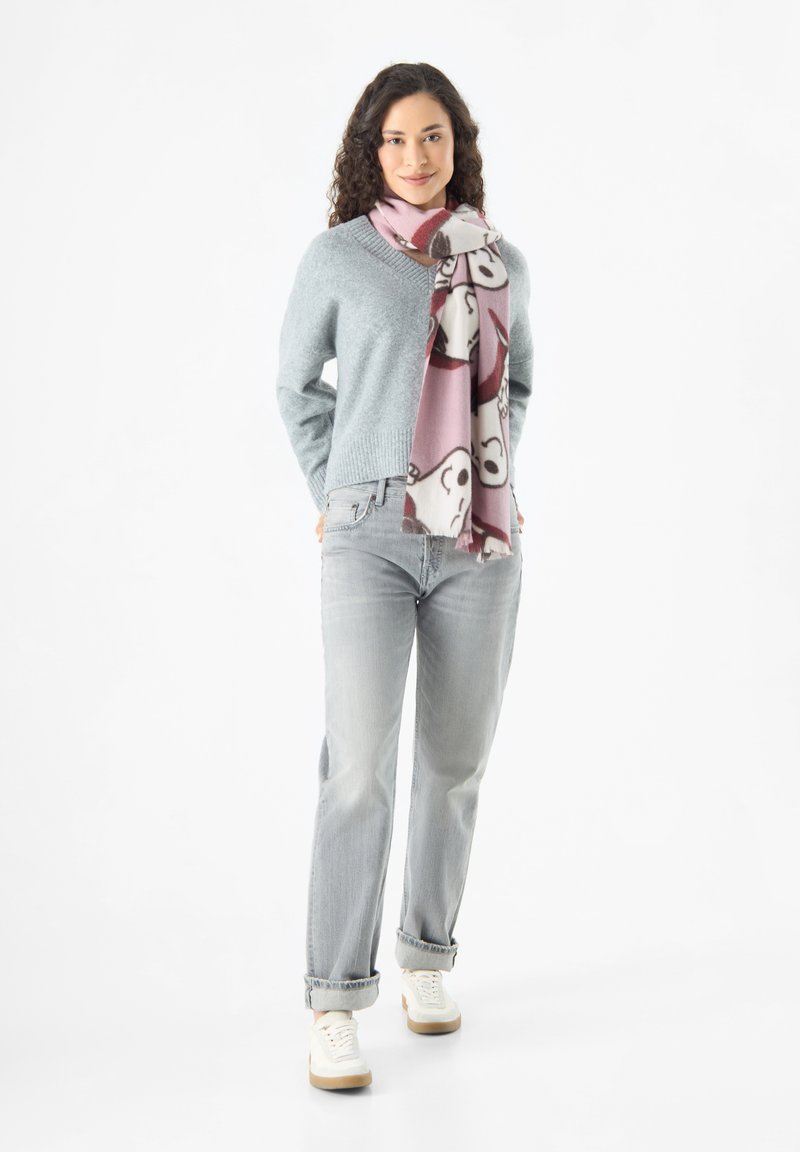 Maglione lavorato a maglia azzurro chiaro con scollo a V, jeans grigi dal taglio rilassato e una sciarpa rosa a fantasia con motivi di animali. Sneakers bianche completano l'outfit.