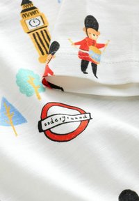 Material cu tematică londoneză, prezentând Big Ben, un toboșar cu uniformă roșie, copaci colorați și logo-ul metroului londonez pe țesătură albă.