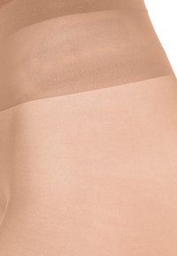 Collant beige trasparenti con una texture liscia e opaca; presenta una sezione della vita più spessa nella parte superiore, che si trasforma in una parte della gamba più leggera.
