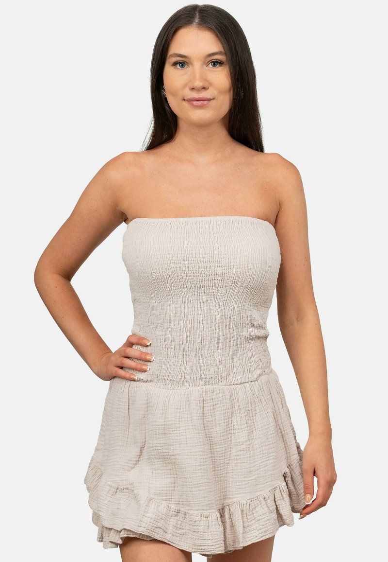 Strapless jurk van lichtbeige stof, met een gerimpelde bustier en een gelaagde rok met ruches. Zacht, textuur en casual ontwerp geschikt voor warm weer.