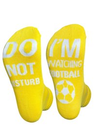 Calcetines amarillos con texto blanco en las plantas: "NO MOLESTAR" y "ESTOY VIENDO FÚTBOL", con un gráfico de un balón de fútbol.